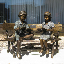 dos niños sentados en el banco leyendo escultura estatua de bronce